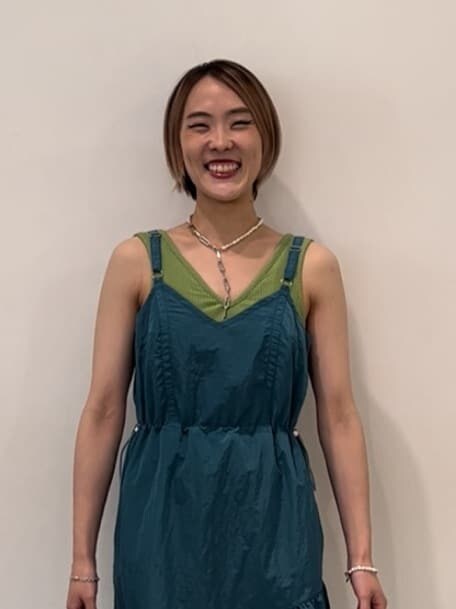 ホワイト系のブーツ、ブルー系のジャンパースカート、グリーン系のキャミソールを着用したレディースの秋コーディネートの3枚目の写真