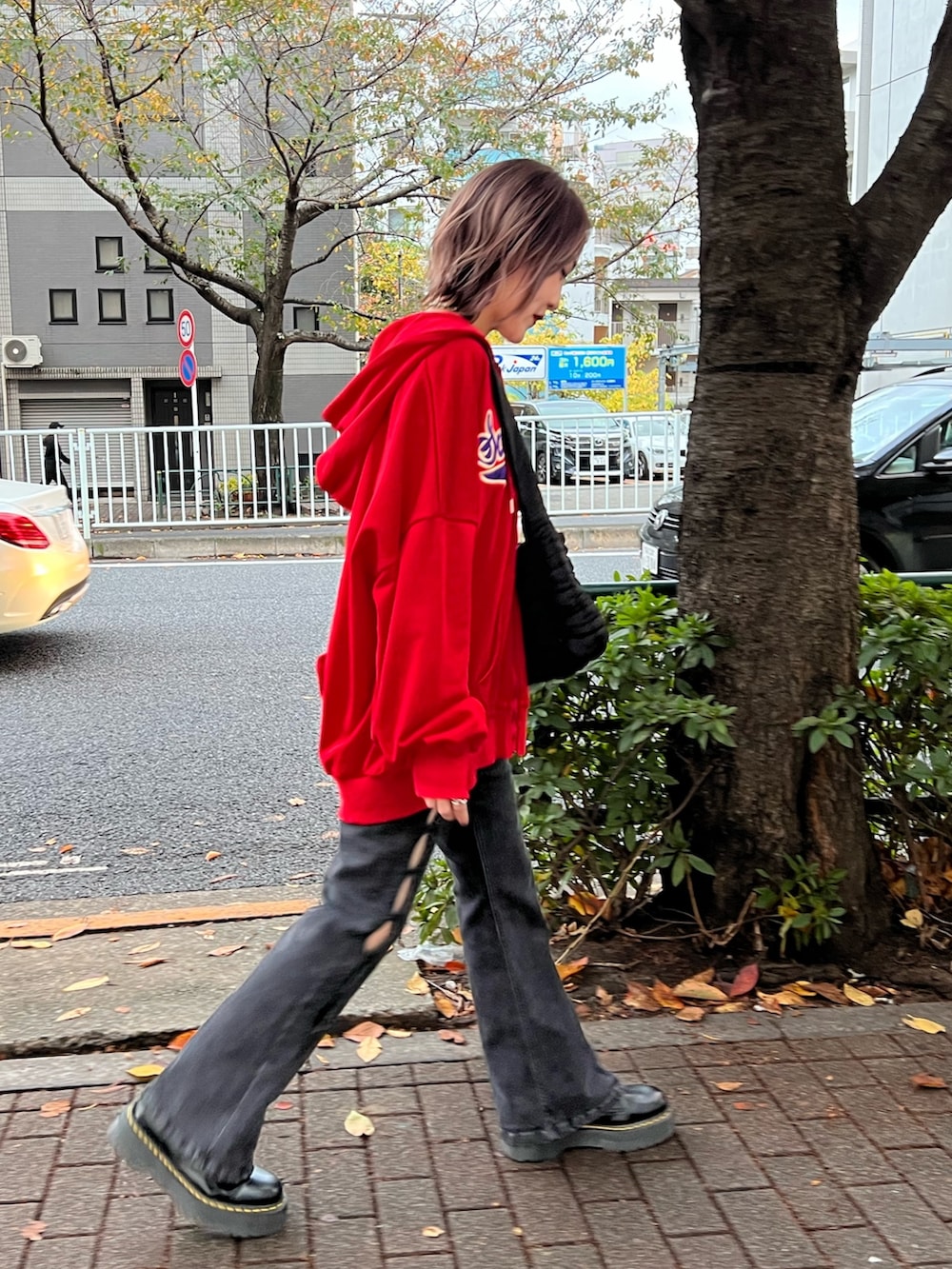 レッド系のパーカー、パープル系のTシャツ/カットソー、ブラック系のデニムパンツを着用したレディースの春コーディネートの4枚目の写真