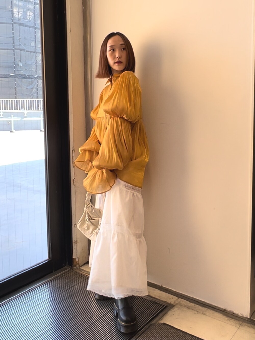 オレンジ系のシャツ/ブラウス、ホワイト系のスカート、ホワイト系のショルダーバッグを着用したレディースの春コーディネートの3枚目の写真