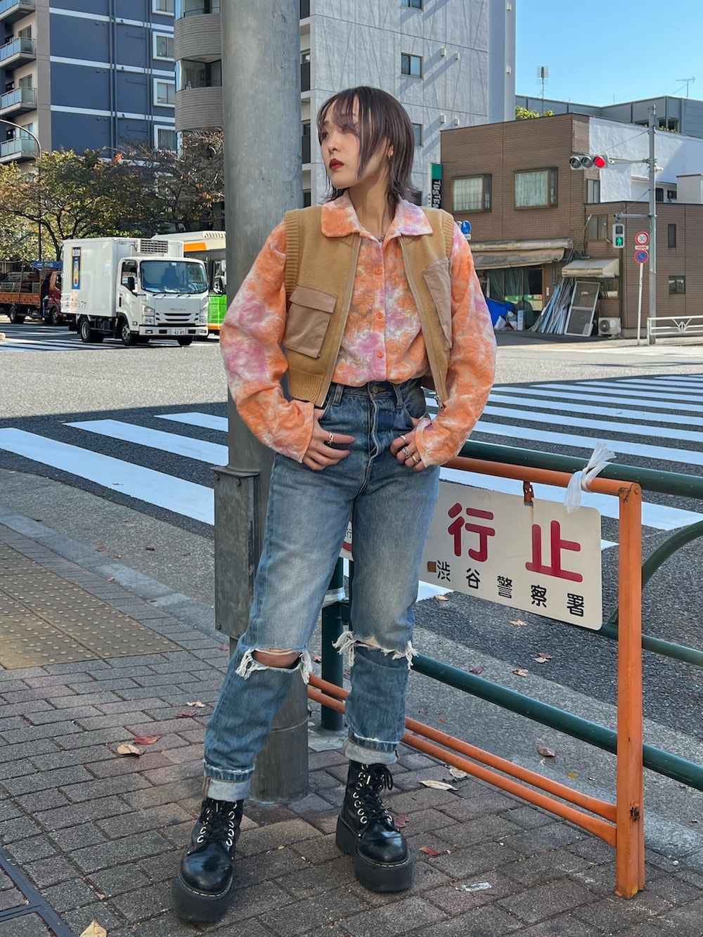 オレンジ系のシャツ/ブラウス、ベージュ系のベスト、ブルー系のデニムパンツを着用したレディースの春コーディネートの2枚目の写真