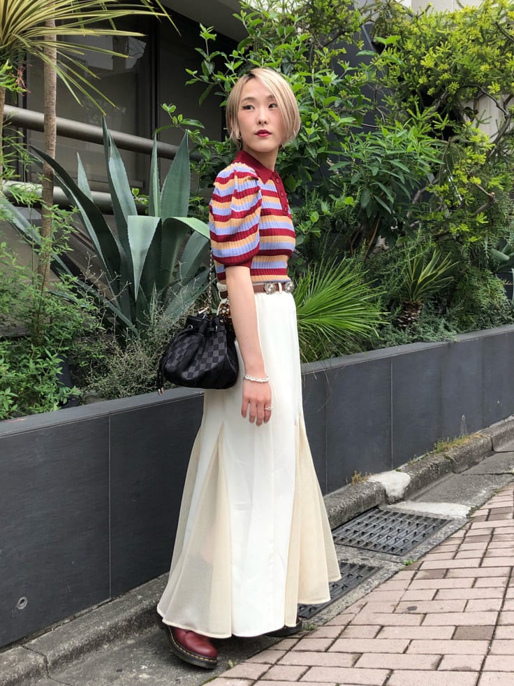 レッド系のニット/セーター、ホワイト系のスカート、ブラック系のショルダーバッグを着用したレディースの夏コーディネートの2枚目の写真