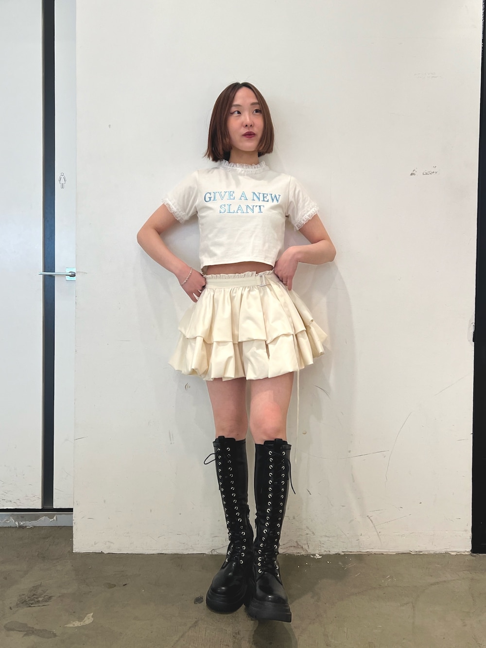 ホワイト系のTシャツ/カットソー、ホワイト系のスカート、ブラック系のブーツを着用したレディースの春コーディネートの2枚目の写真