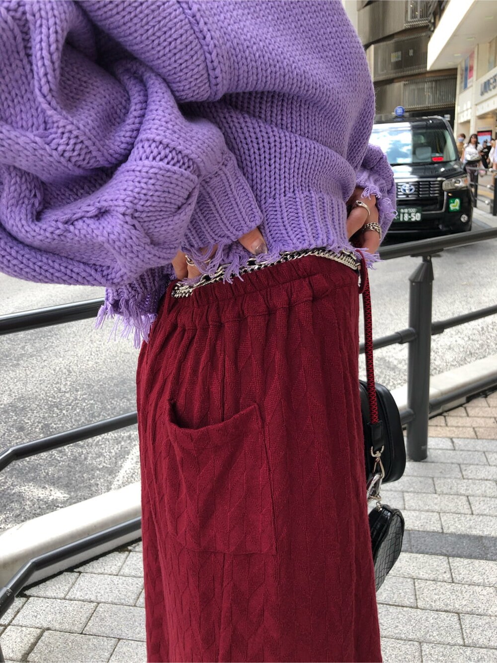 ブラック系のブーツ、ブラック系のショルダーバッグ、パープル系のニット/セーターを着用したレディースの秋コーディネートの6枚目の写真