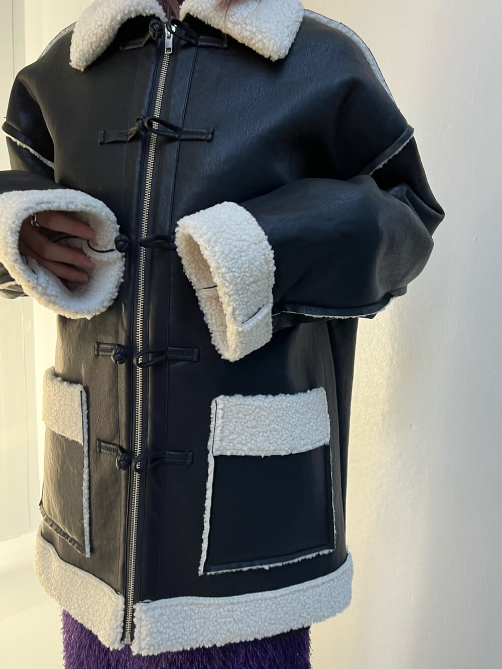 ブラック系のムートンコート、パープル系のスカート、ブラック系のスウェットを着用したレディースの夏コーディネートの7枚目の写真