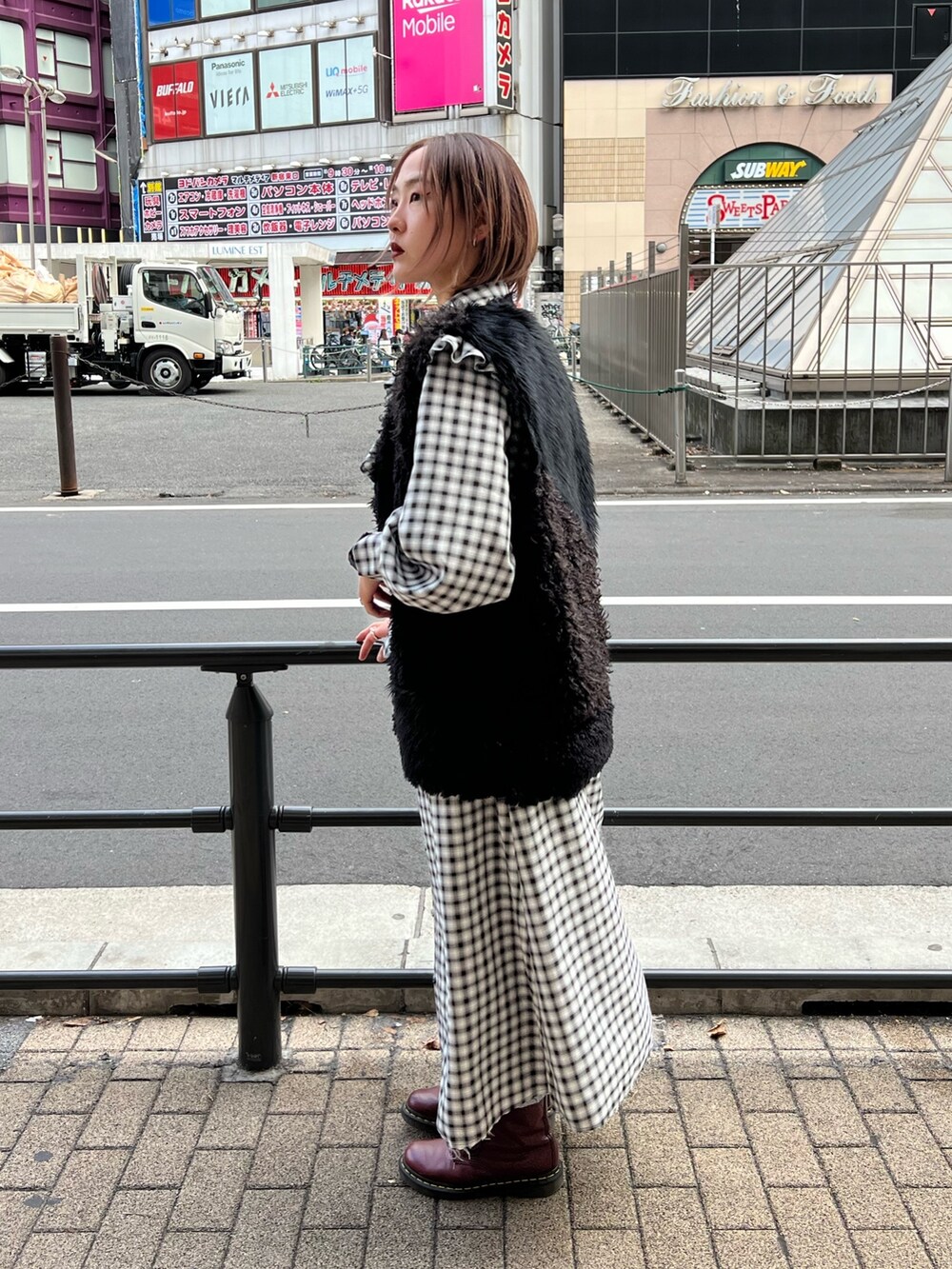 ブラック系のワンピース、ブラック系のベスト、ブルー系のデニムパンツを着用したレディースの冬コーディネートの3枚目の写真