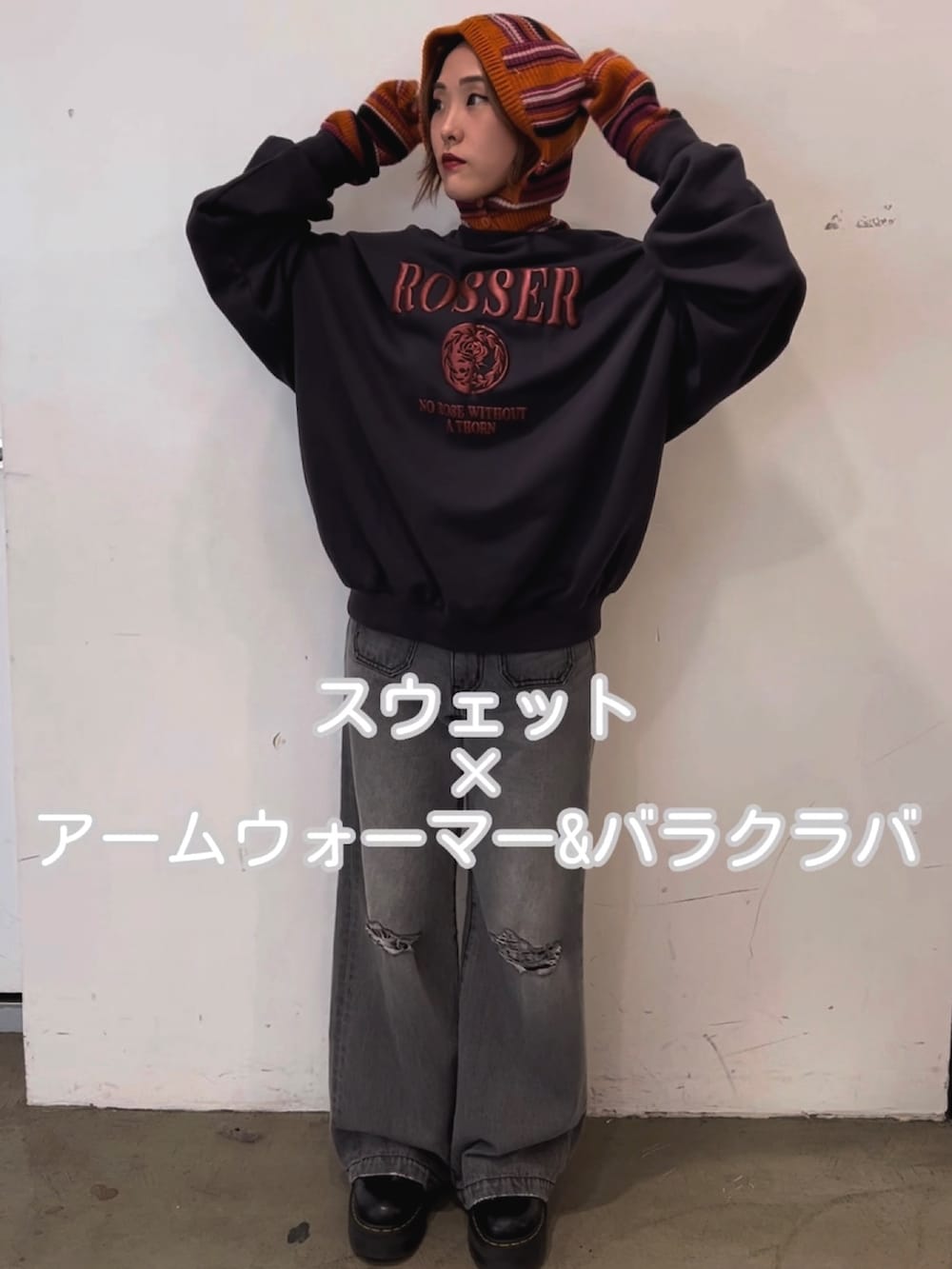 ブラック系のスウェット、ブラック系のデニムパンツ、ピンク系のアームカバーを着用したレディースの秋コーディネートの3枚目の写真