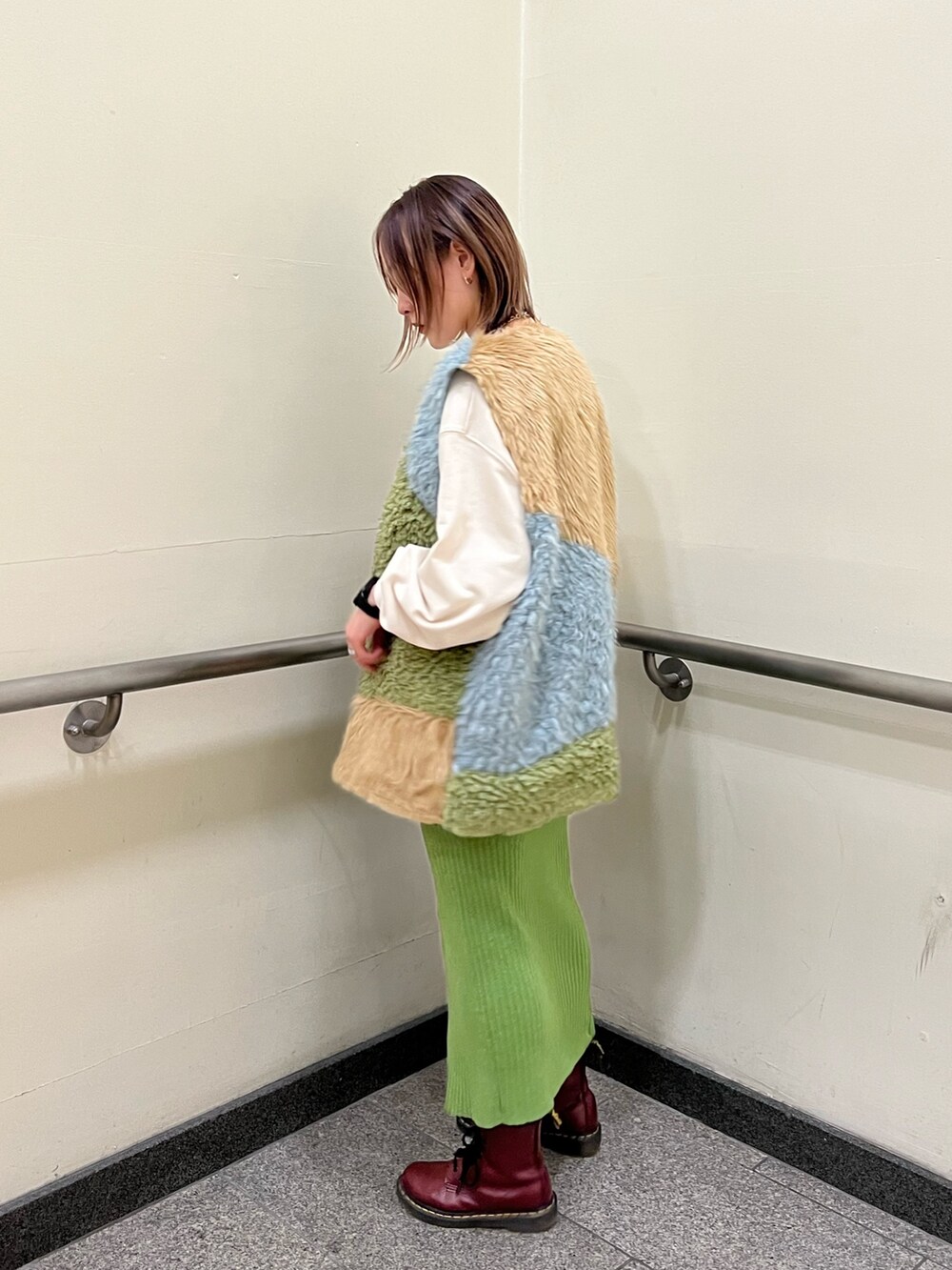 その他のベスト、ホワイト系のニット/セーター、グリーン系のスカートを着用したレディースの冬コーディネートの2枚目の写真