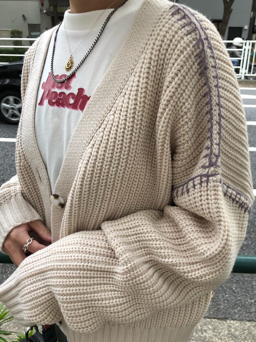 ブラック系のショルダーバッグ、ベージュ系のワンピース、ホワイト系のカーディガン/ボレロを着用したレディースの秋コーディネートの5枚目の写真