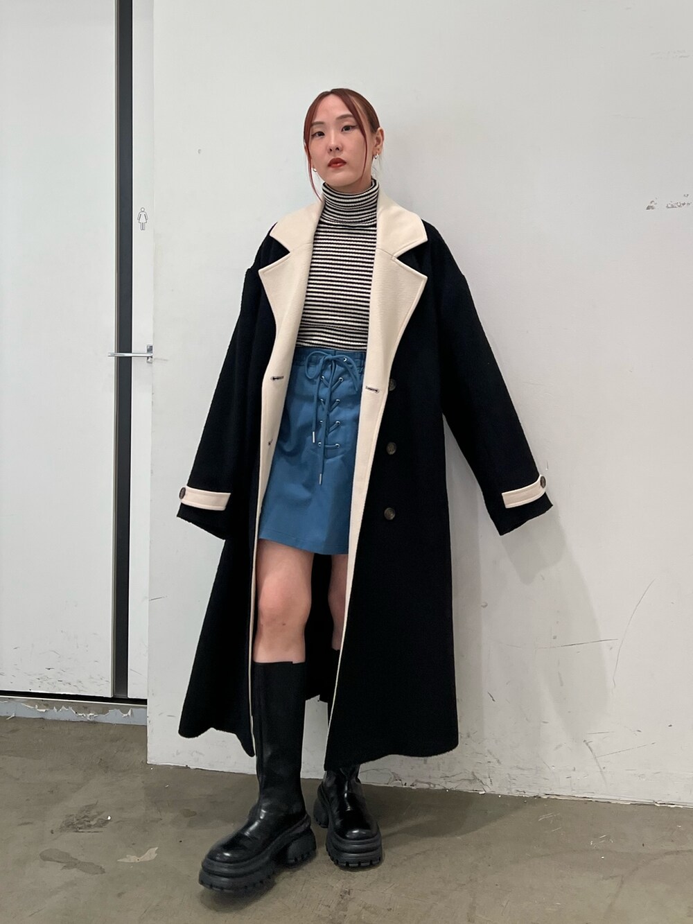 その他のニット/セーター、ブルー系のスカート、ブラック系のチェスターコートを着用したレディースの秋コーディネートの2枚目の写真