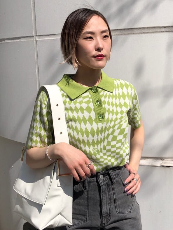 グリーン系のニット/セーター、ブラック系のデニムパンツ、ホワイト系のハンドバッグを着用したレディースの夏コーディネートの4枚目の写真