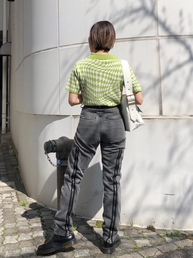 グリーン系のニット/セーター、ブラック系のデニムパンツ、ホワイト系のハンドバッグを着用したレディースの夏コーディネートの3枚目の写真