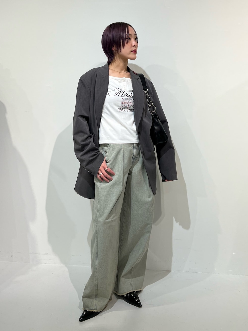 グレー系のテーラードジャケット、ブラック系のパンプス、ブルー系のデニムパンツを着用したレディースの春コーディネートの2枚目の写真