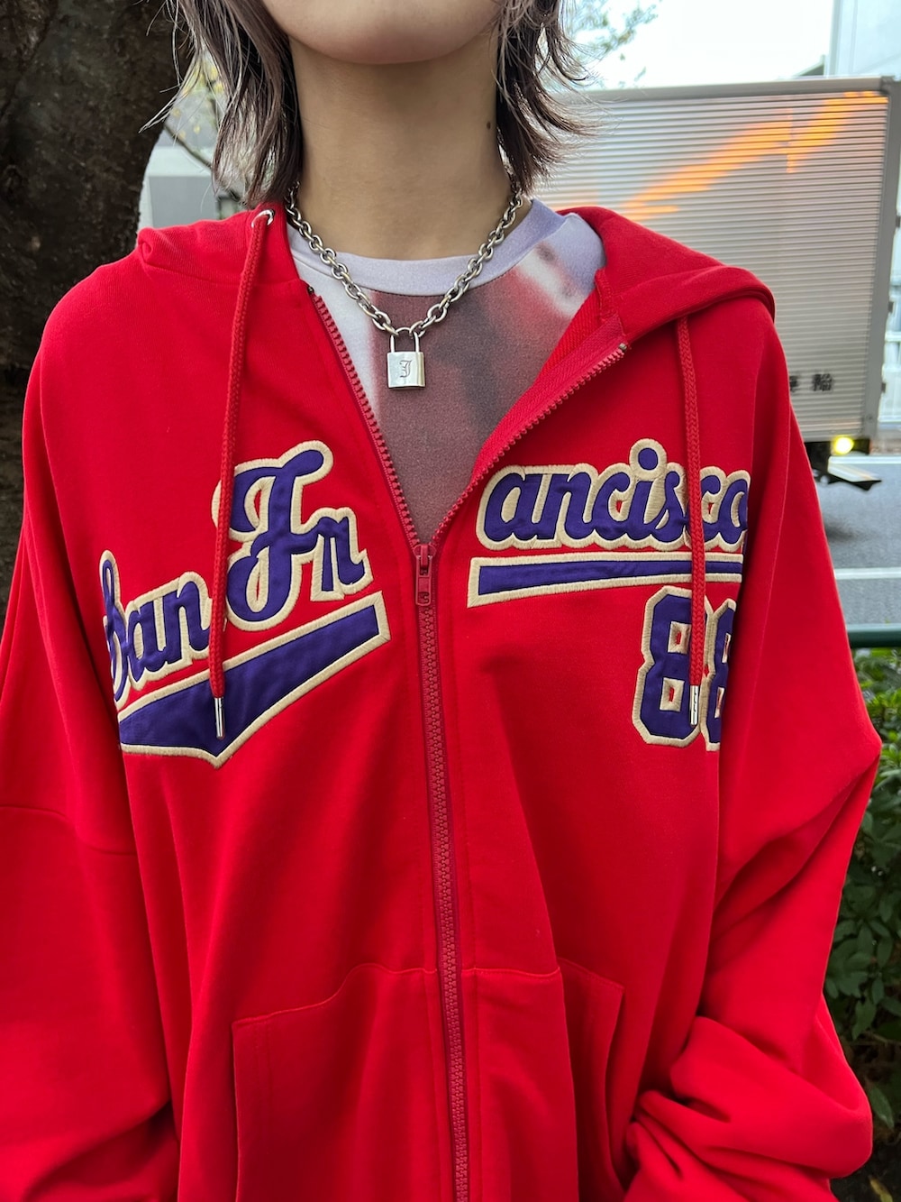 レッド系のパーカー、パープル系のTシャツ/カットソー、ブラック系のデニムパンツを着用したレディースの春コーディネートの6枚目の写真