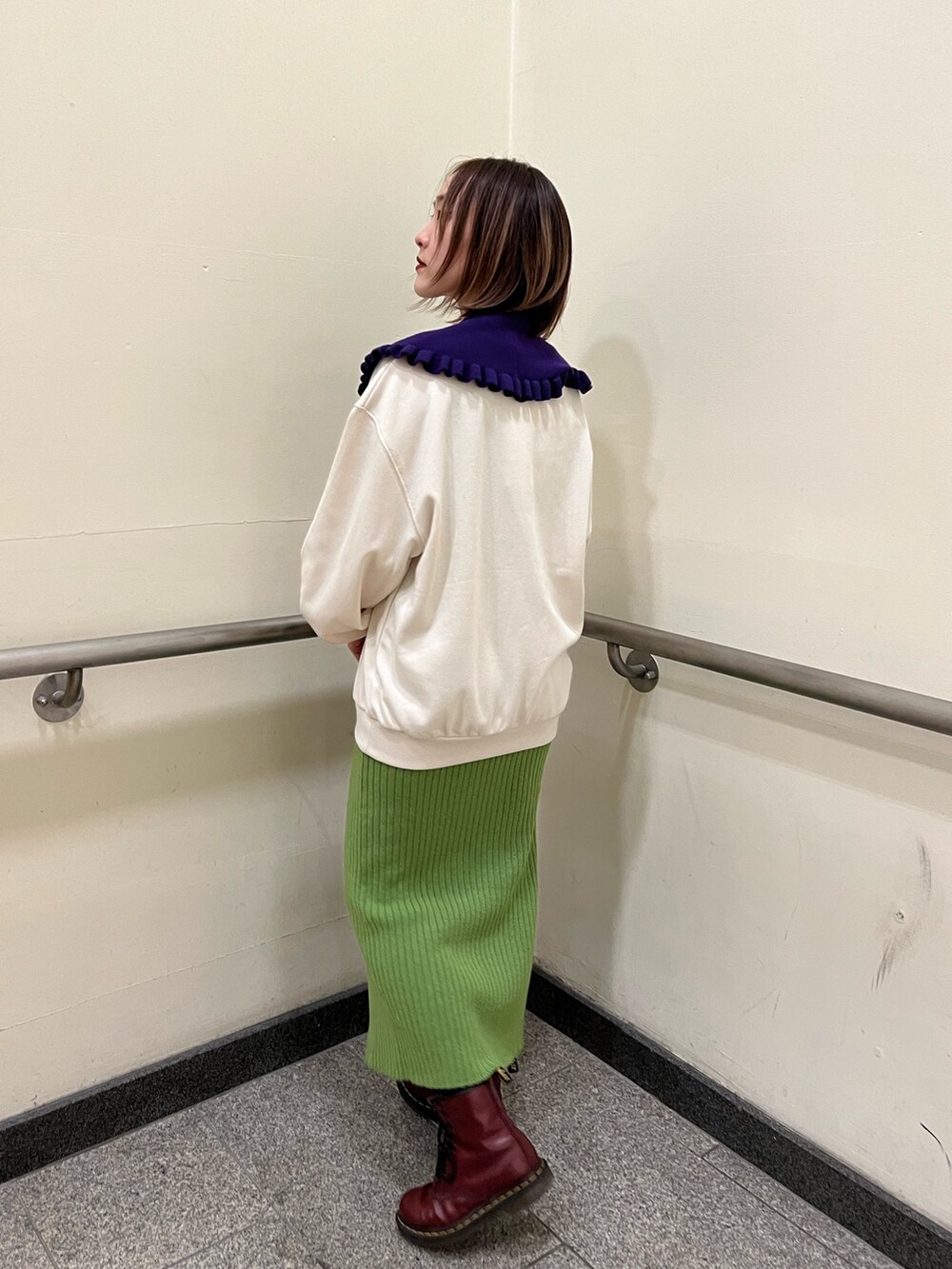 グリーン系のスカート、ホワイト系のニット/セーターを着用したレディースの冬コーディネートの3枚目の写真