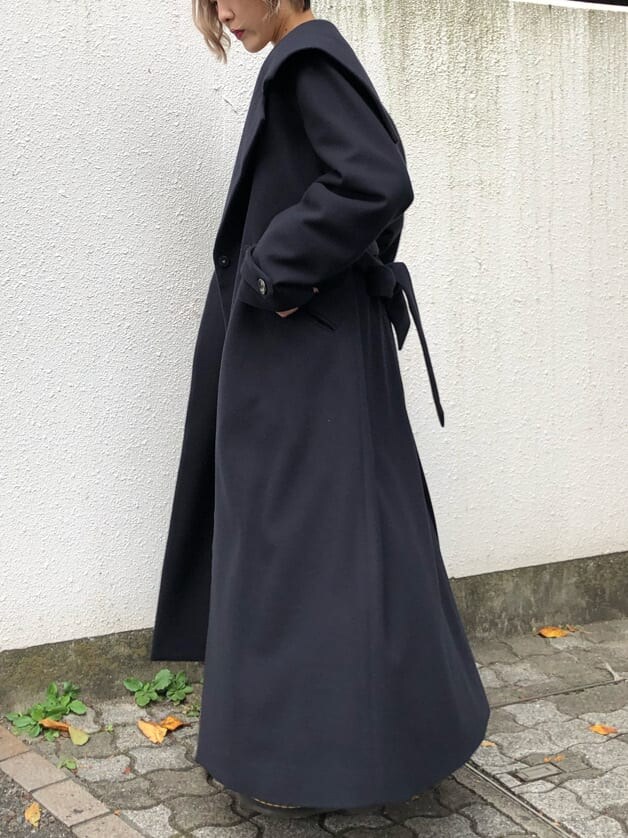 ブルー系のチェスターコート、ブラック系のデニムパンツ、ブラック系のニット/セーターを着用したレディースの秋コーディネートの2枚目の写真