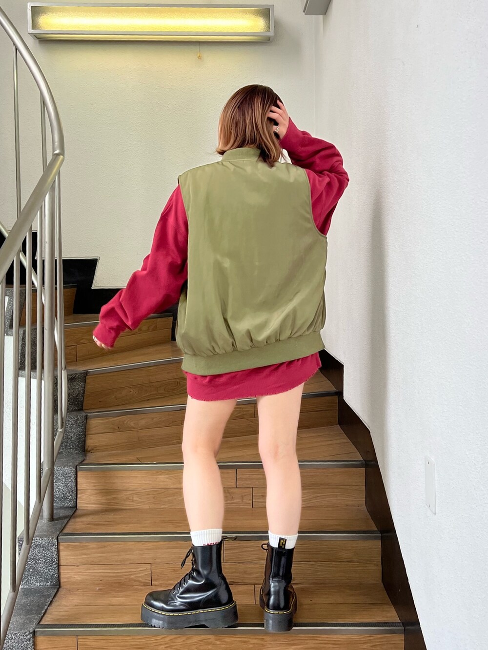 レッド系のスウェット、グリーン系のMA-1、ブラック系のデニムパンツを着用したレディースの冬コーディネートの3枚目の写真