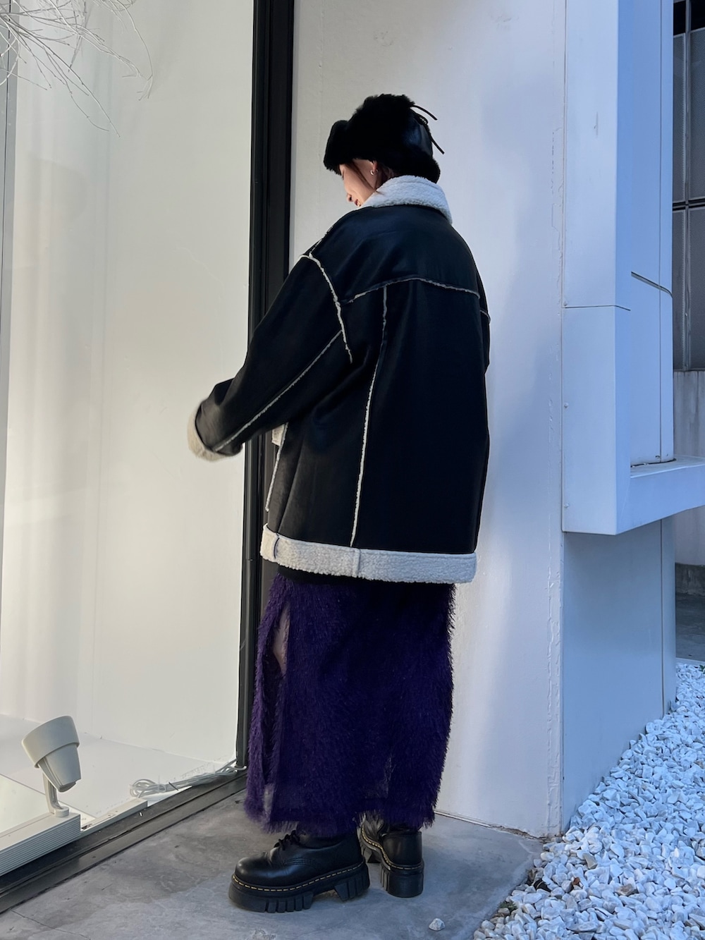 ブラック系のムートンコート、パープル系のスカート、ブラック系のスウェットを着用したレディースの夏コーディネートの4枚目の写真