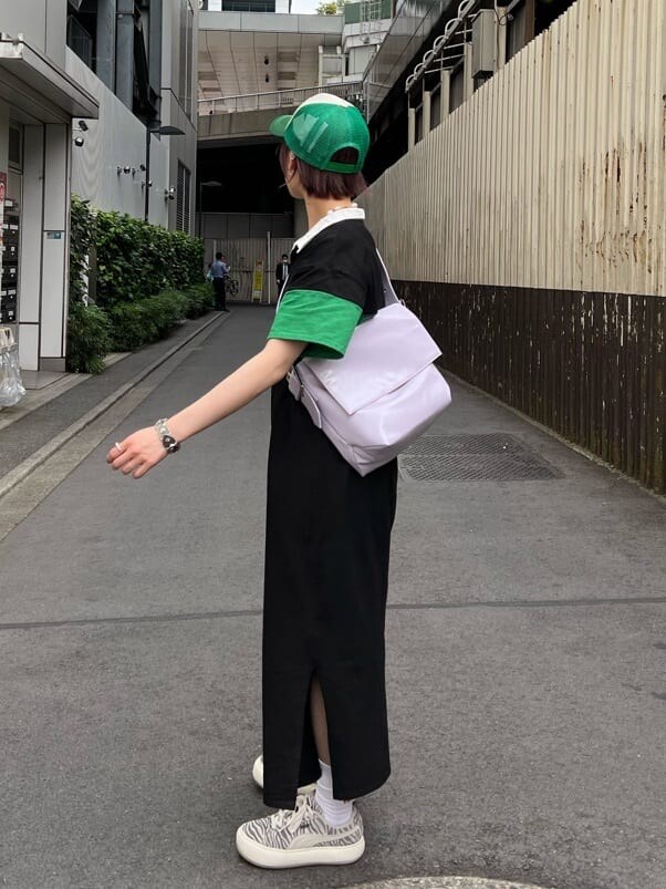 ブラック系のワンピース、パープル系のハンドバッグ、グリーン系のキャップを着用したレディースの夏コーディネートの3枚目の写真
