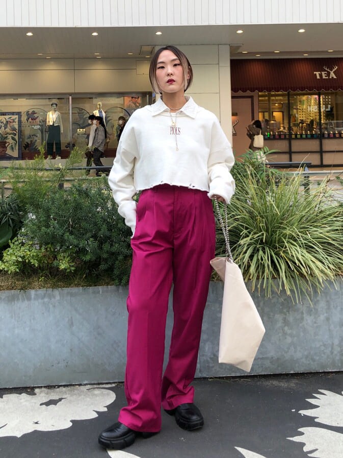 ピンク系のスラックス、ホワイト系のトートバッグ、ブラック系のブーツを着用したレディースの春コーディネートの2枚目の写真