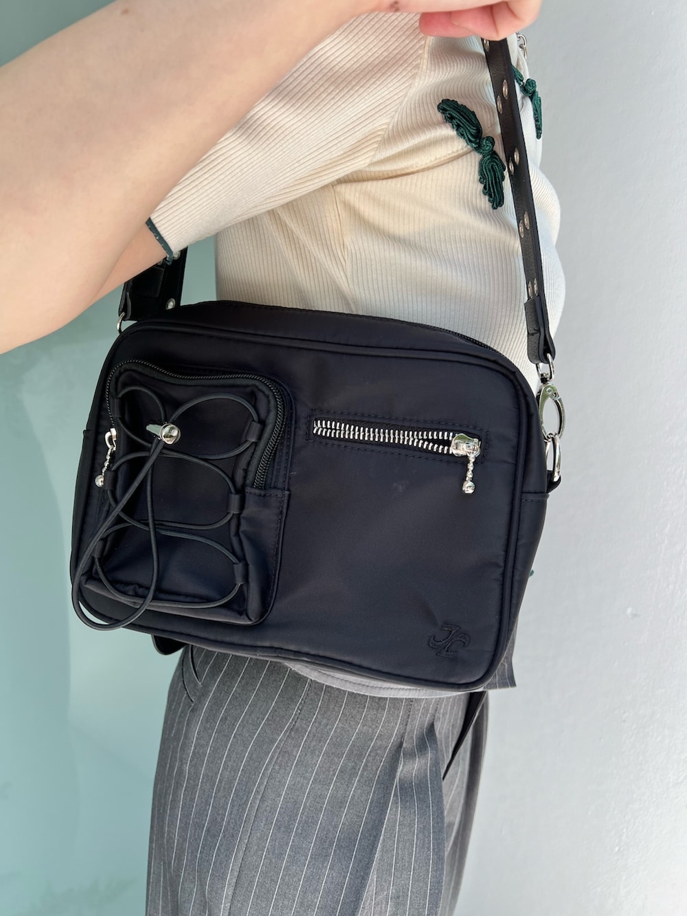 ホワイト系のポロシャツ、グレー系のスラックス、ブラック系のショルダーバッグを着用したレディースの夏コーディネートの9枚目の写真