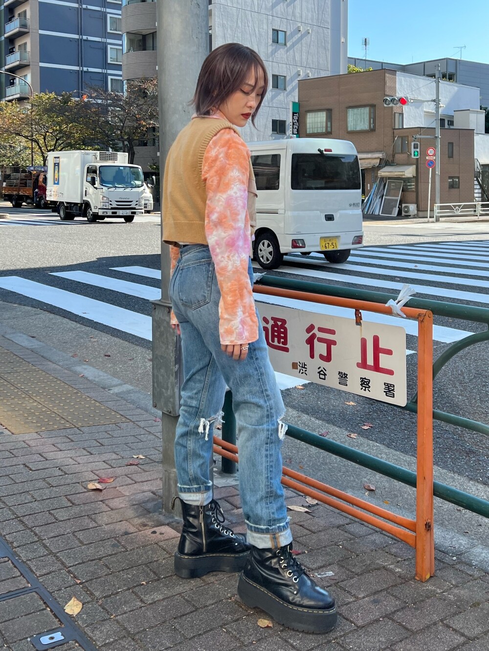 オレンジ系のシャツ/ブラウス、ベージュ系のベスト、ブルー系のデニムパンツを着用したレディースの春コーディネートの5枚目の写真