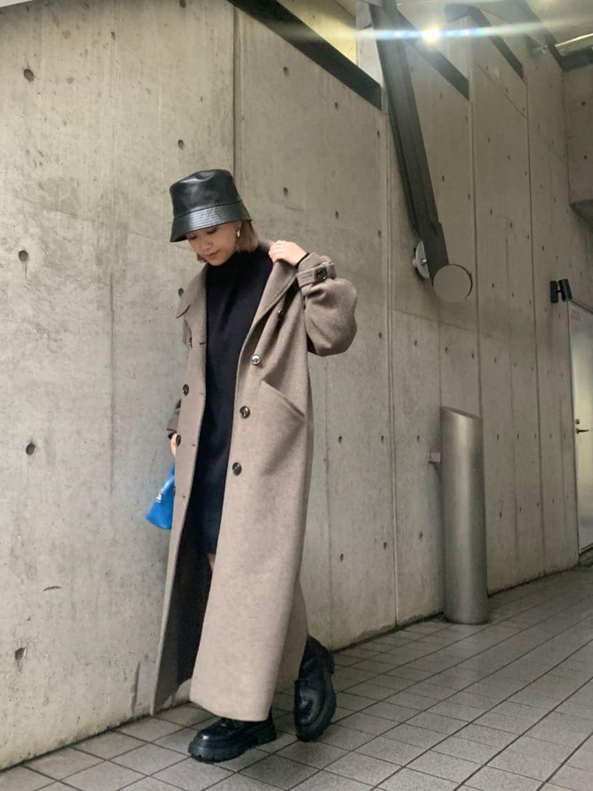 ブラック系のワンピース、ベージュ系のチェスターコート、ブラック系のブーツを着用したレディースの冬コーディネートの2枚目の写真