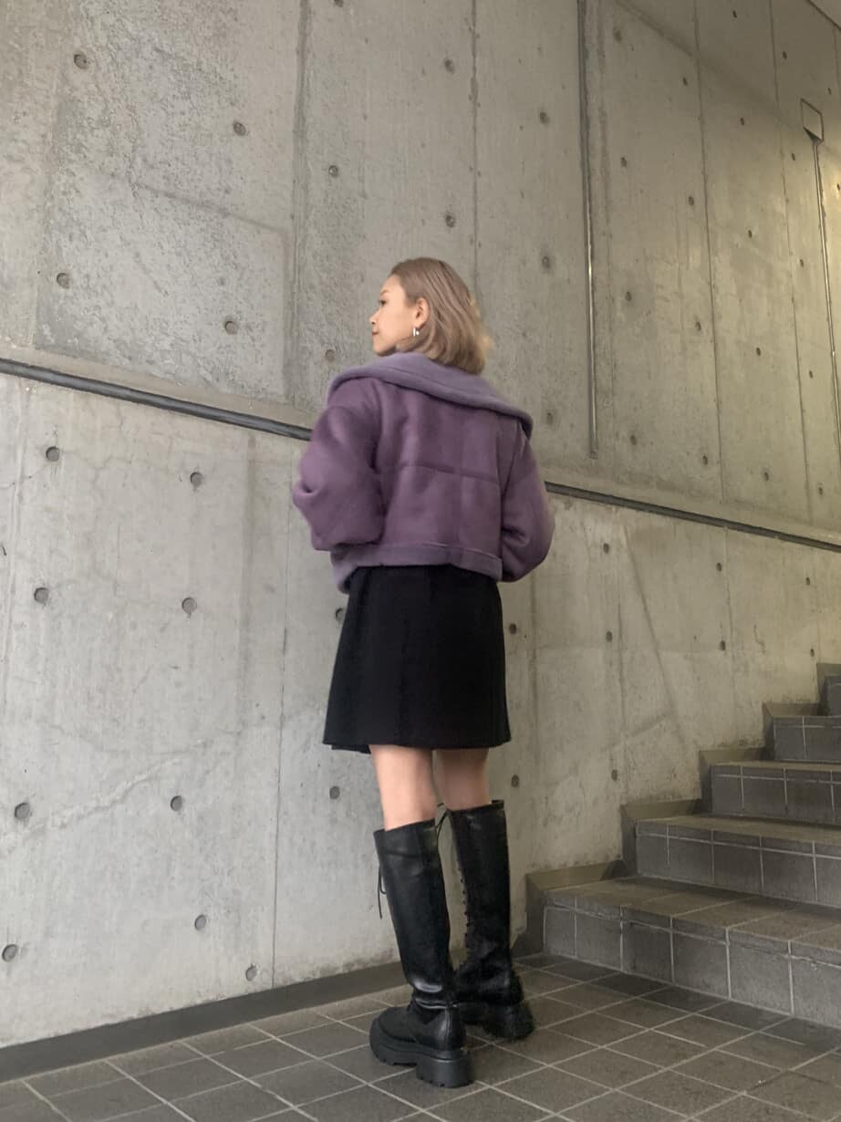 パープル系のブルゾン、ブラック系のワンピース、ブラック系のブーツを着用したレディースの冬コーディネートの2枚目の写真