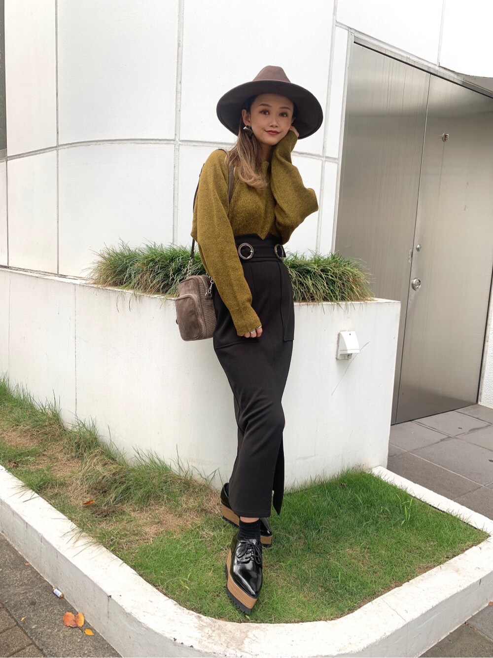 ブラック系のスカート、ブラック系のローファー、ベージュ系のニット/セーターを着用したレディースの秋コーディネートの3枚目の写真