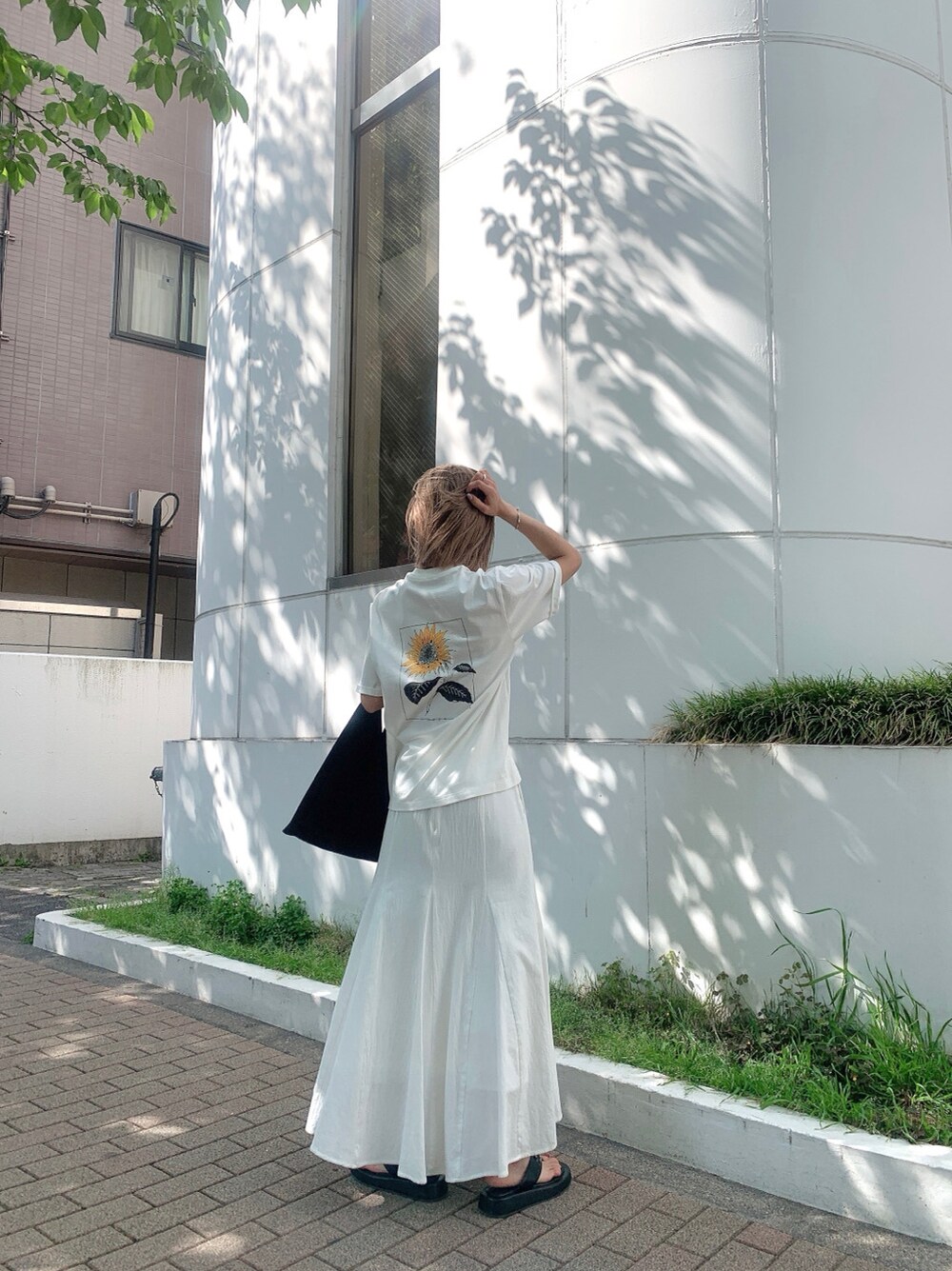 ホワイト系のスカート、ブラック系のサンダル、ホワイト系のTシャツ/カットソーを着用したレディースの春コーディネートの3枚目の写真