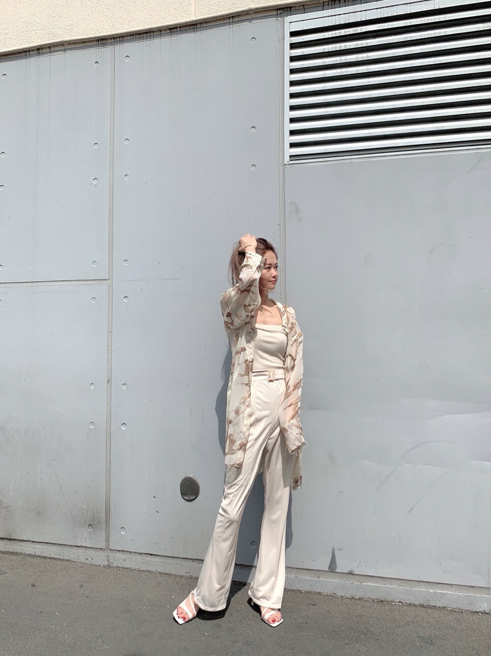 ホワイト系のスラックス、ホワイト系のサンダル、ホワイト系のTシャツ/カットソーを着用したレディースの春コーディネートの2枚目の写真