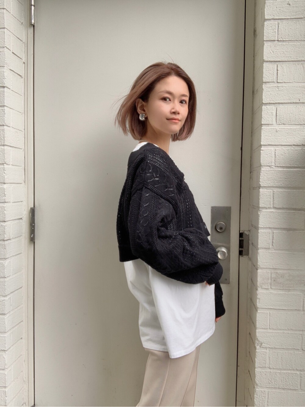 ホワイト系のその他パンツ、ホワイト系のサンダル、ブラック系のニット/セーターを着用したレディースの春コーディネートの2枚目の写真