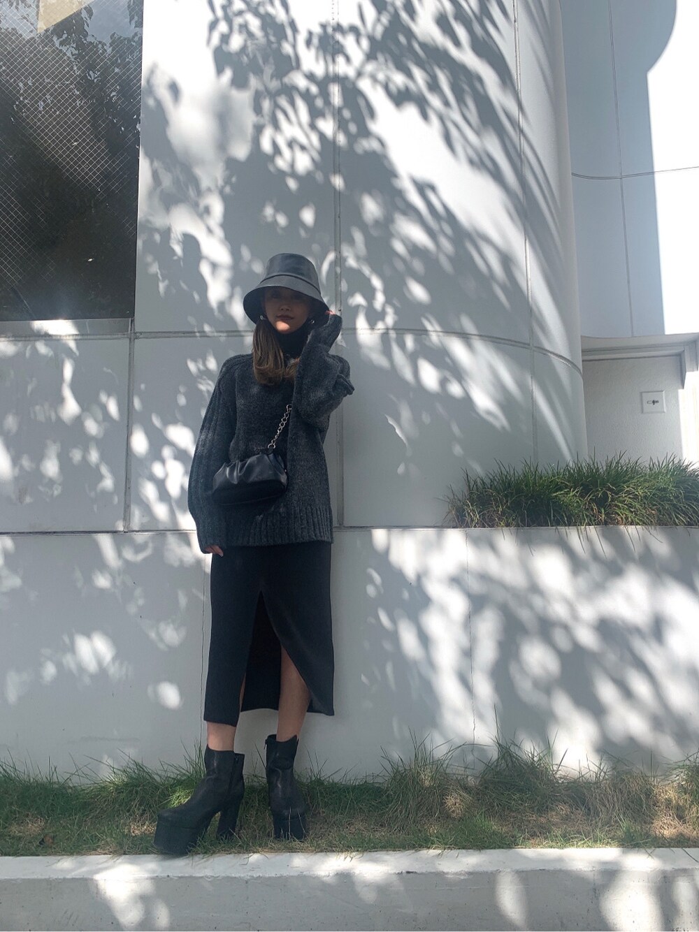 ブラック系のブーツ、ブラック系のハンドバッグ、グレー系のニット/セーターを着用したレディースの秋コーディネートの2枚目の写真