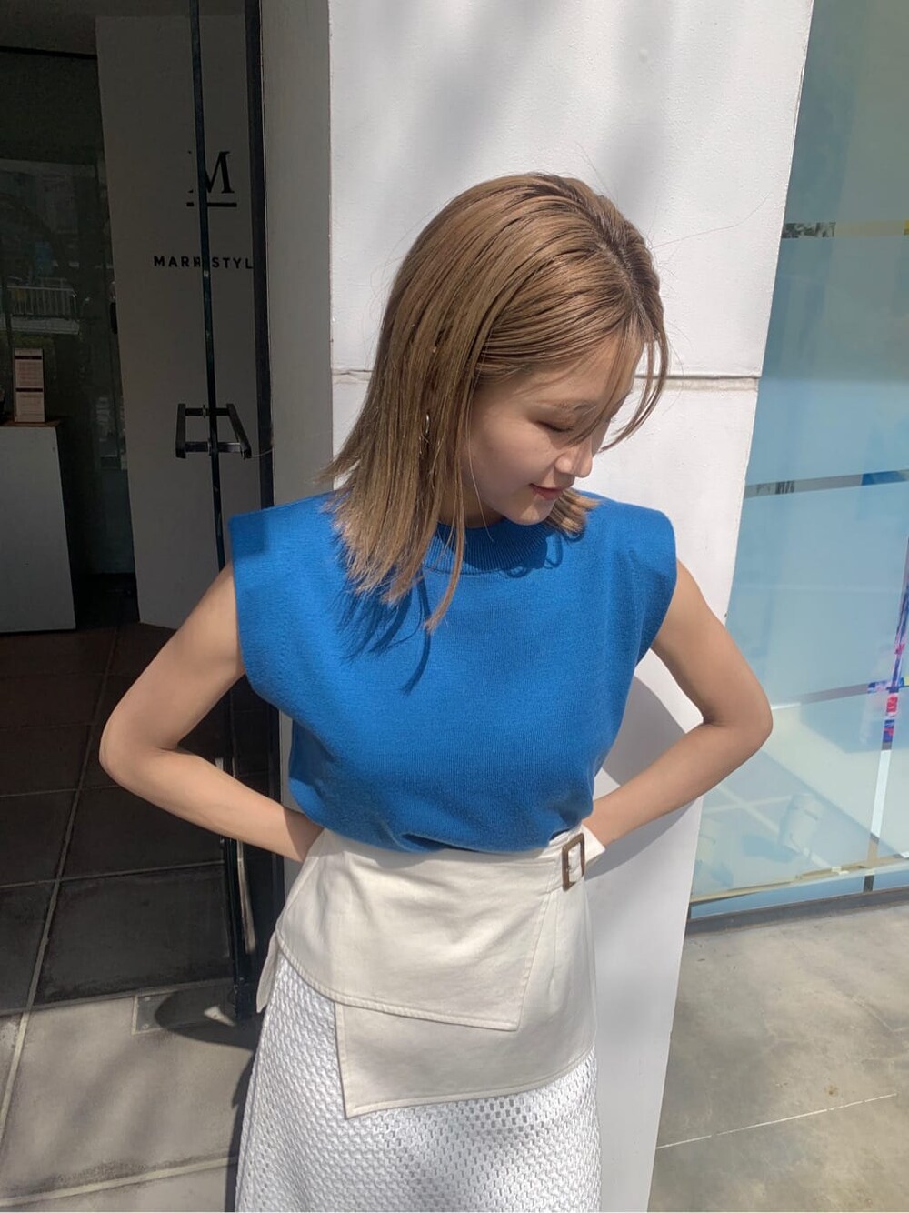 ホワイト系のスカート、ブラック系のサンダル、ブルー系のタンクトップを着用したレディースの春コーディネートの4枚目の写真