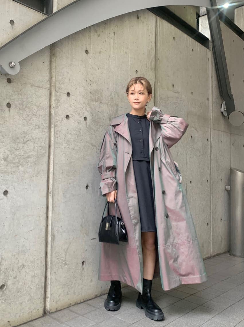 ベージュ系のトレンチコート、ブルー系のワンピース、ブラック系のブーツを着用したレディースの冬コーディネートの3枚目の写真