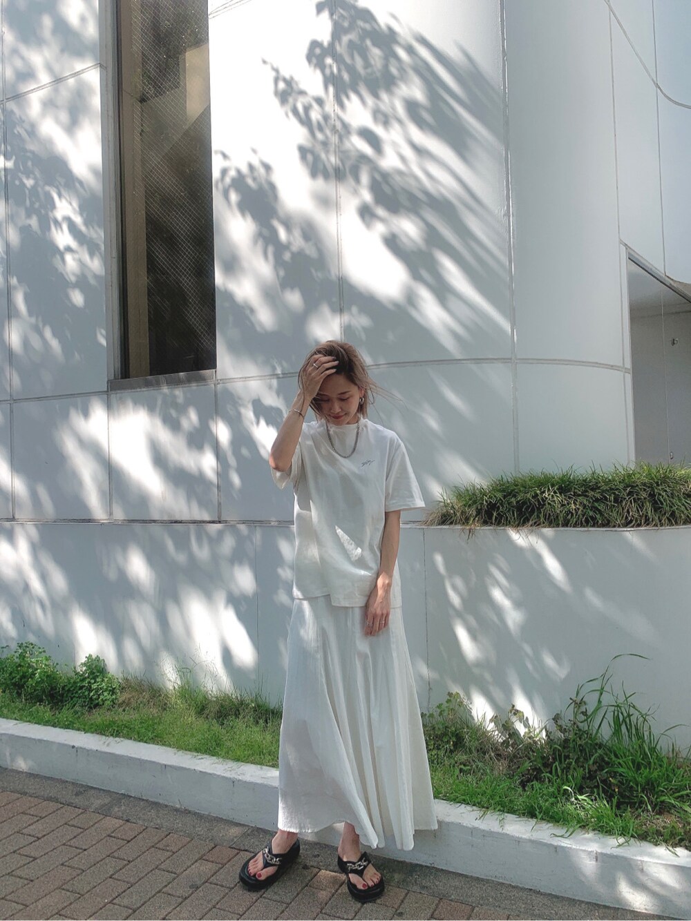 ホワイト系のスカート、ブラック系のサンダル、ホワイト系のTシャツ/カットソーを着用したレディースの春コーディネートの2枚目の写真