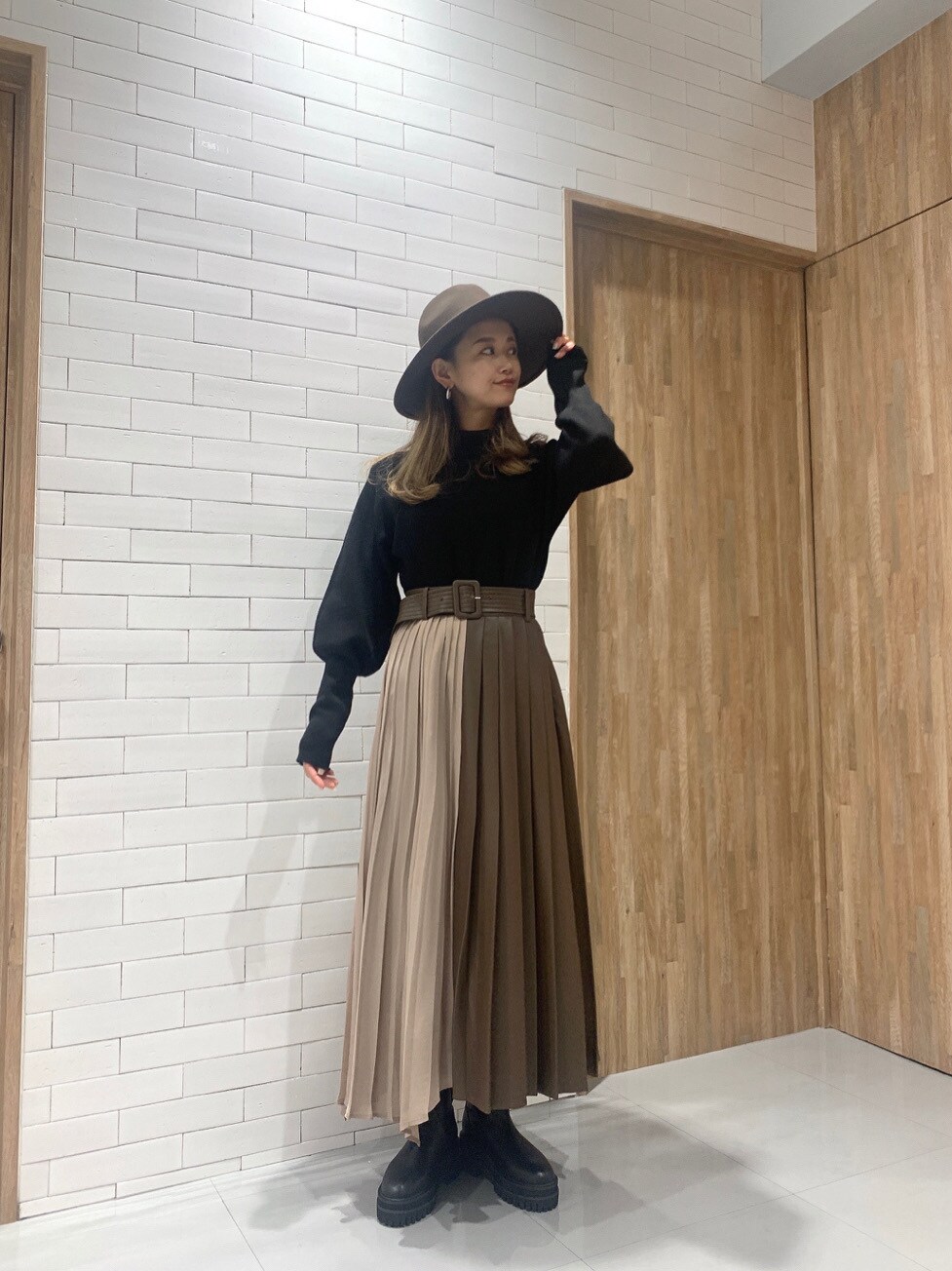 ブラウン系のスカート、ブラック系のニット/セーター、ブラウン系のハットを着用したレディースの冬コーディネートの2枚目の写真