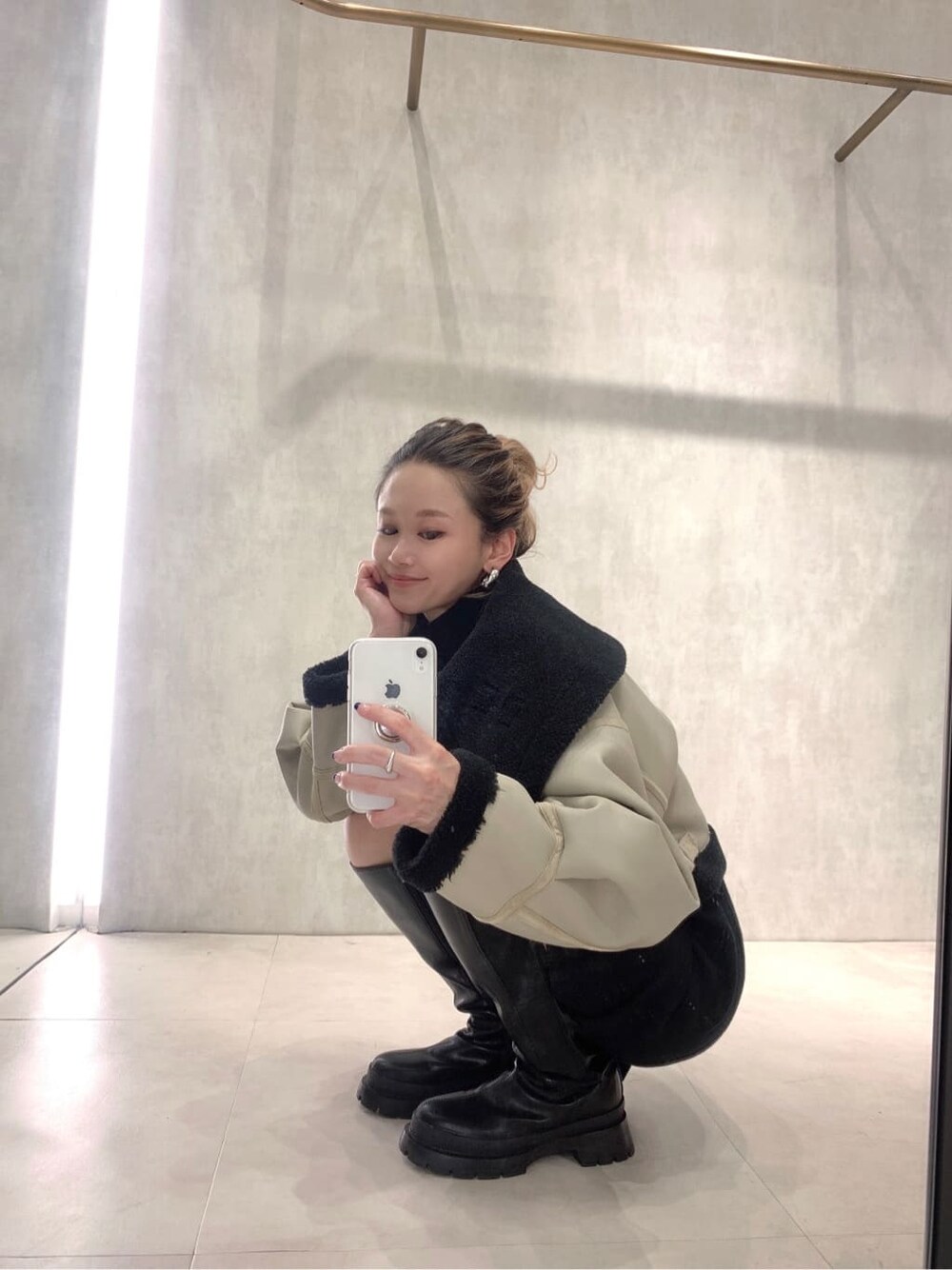 ホワイト系のブルゾン、ブラック系のワンピース、ブラック系のブーツを着用したレディースの秋コーディネートの2枚目の写真