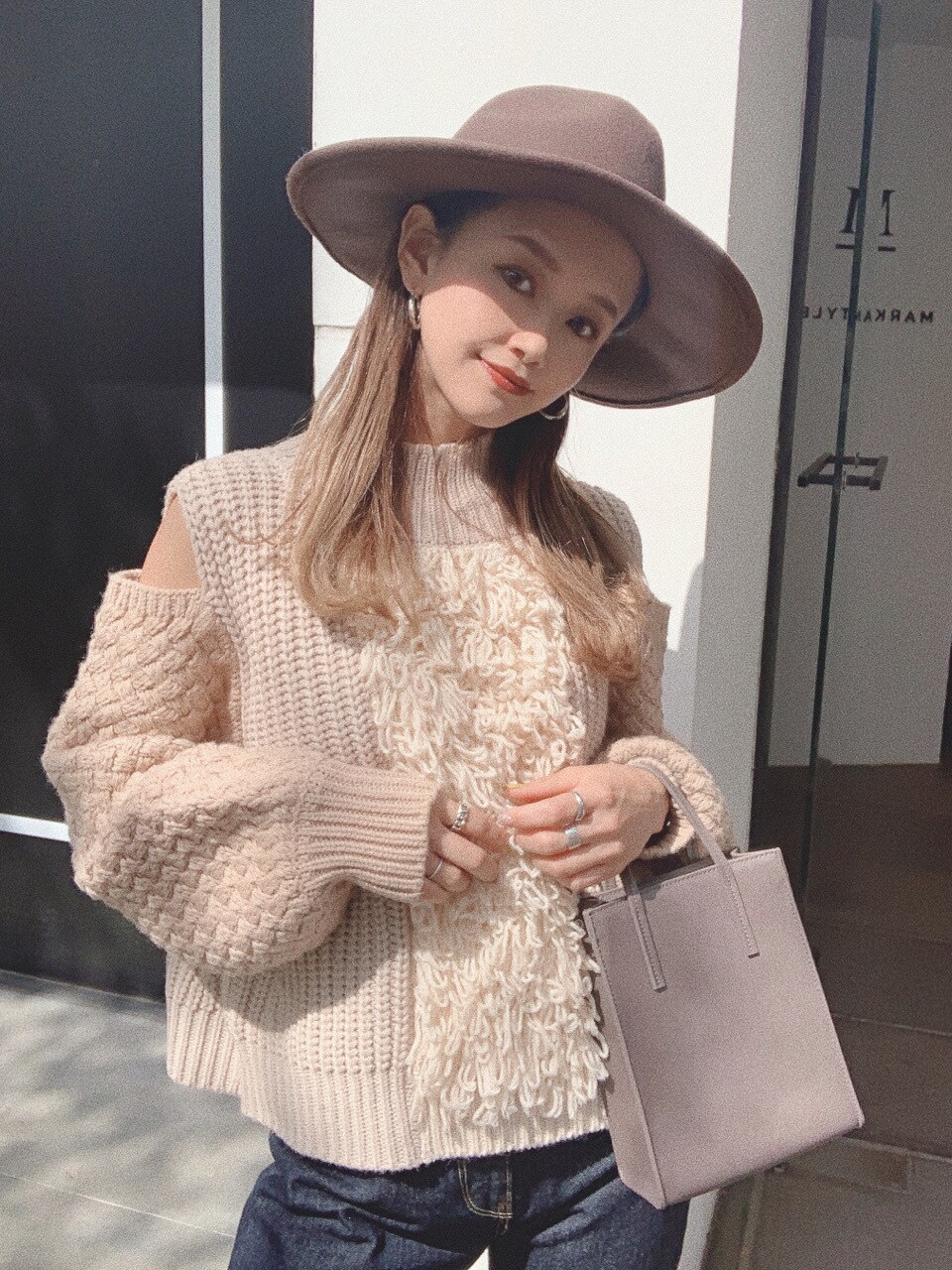 ベージュ系のショルダーバッグ、ブルー系のデニムパンツ、ベージュ系のニット/セーターを着用したレディースの秋コーディネートの2枚目の写真