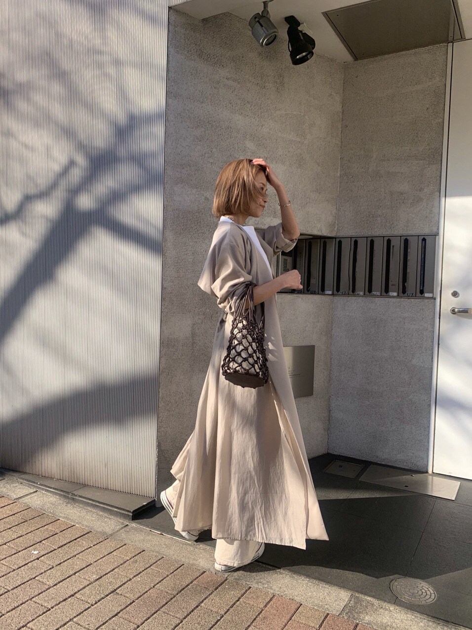ホワイト系のその他パンツ、ベージュ系のその他アウター、ブラウン系のハンドバッグを着用したレディースの春コーディネートの2枚目の写真
