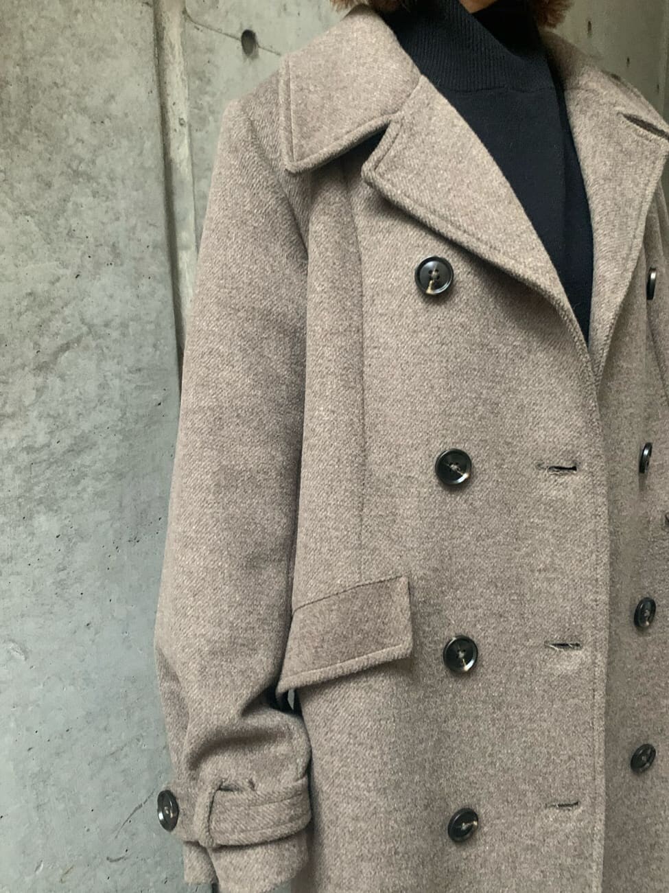 ブラック系のワンピース、ベージュ系のチェスターコート、ブラック系のブーツを着用したレディースの冬コーディネートの4枚目の写真