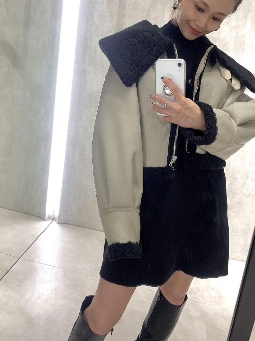 ホワイト系のブルゾン、ブラック系のワンピース、ブラック系のブーツを着用したレディースの秋コーディネートの3枚目の写真