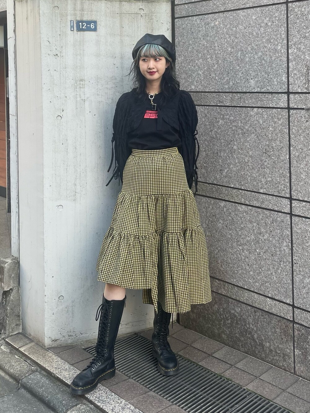 イエロー系のスカート、ブラック系のカーディガン/ボレロ、ブラック系のTシャツ/カットソーを着用したレディースの春コーディネートの2枚目の写真