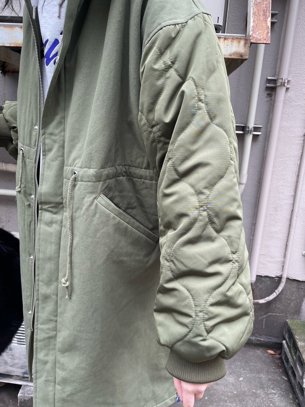 グリーン系のモッズコート、ブラック系のスカート、ブラック系のブーツを着用したレディースの秋コーディネートの6枚目の写真