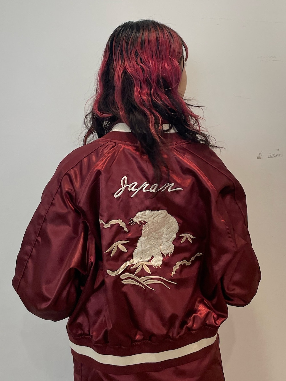 ホワイト系のニット/セーター、レッド系のスカジャン、レッド系のスカートを着用したレディースの春コーディネートの5枚目の写真