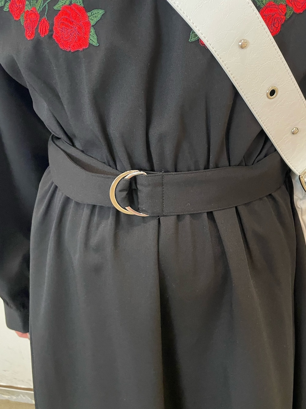 ホワイト系のショルダーバッグ、ブラック系のワンピース、ブラック系のブーツを着用したレディースの冬コーディネートの6枚目の写真