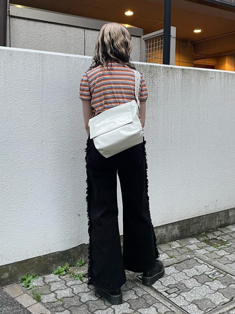 ブラック系のブーツ、ホワイト系のハンドバッグ、ブラック系のデニムパンツを着用したレディースの夏コーディネートの3枚目の写真