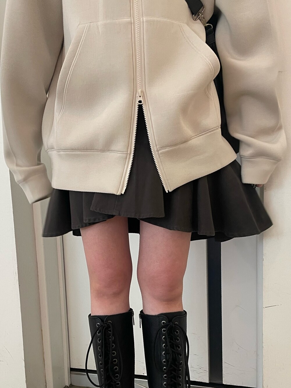 ホワイト系のパーカー、ブラック系のバックパック/リュック、ブラック系のスカートを着用したレディースの冬コーディネートの6枚目の写真