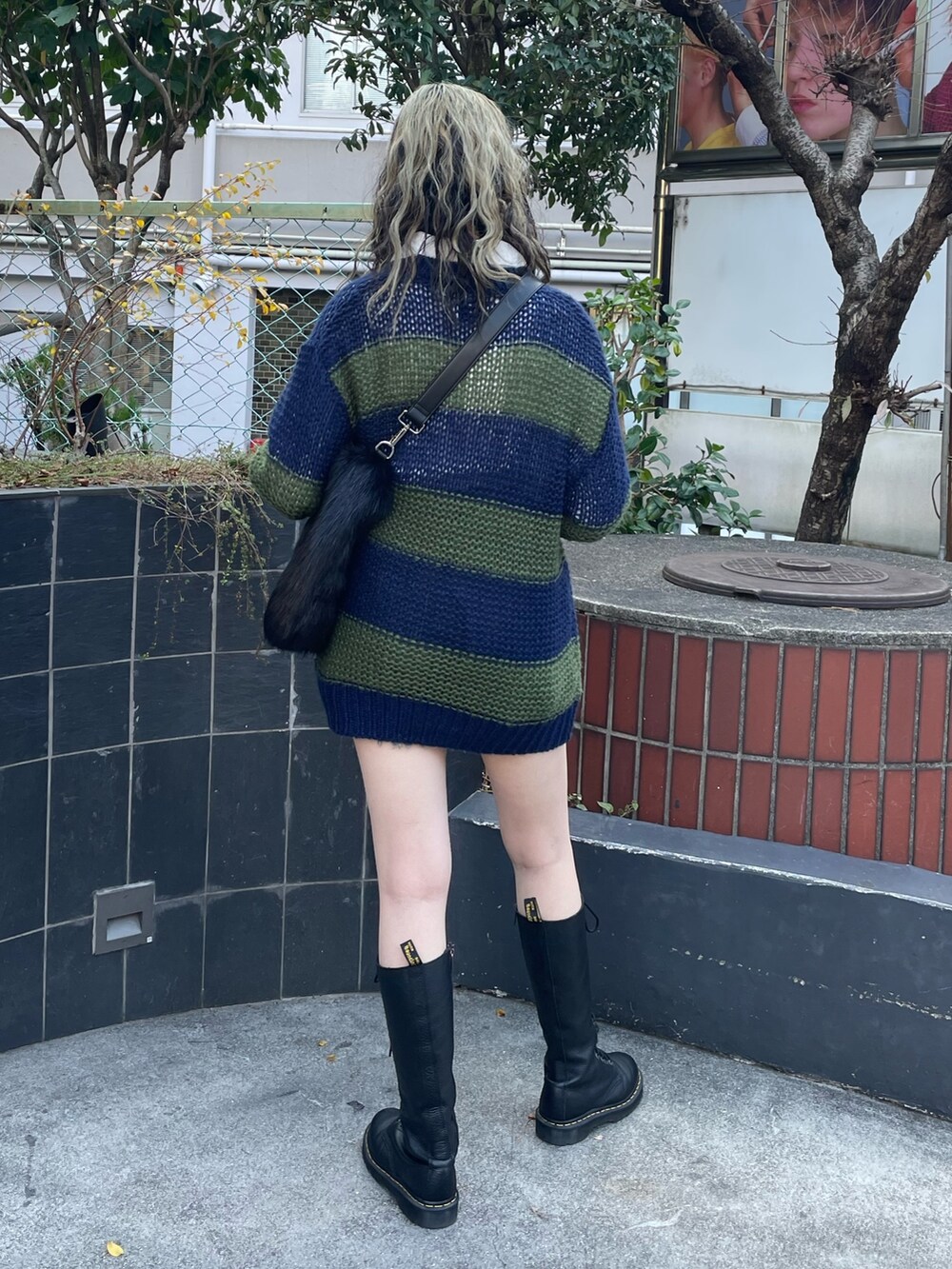 ブラック系のショルダーバッグ、ブラック系のブーツ、ブルー系のニット/セーターを着用したレディースの冬コーディネートの3枚目の写真