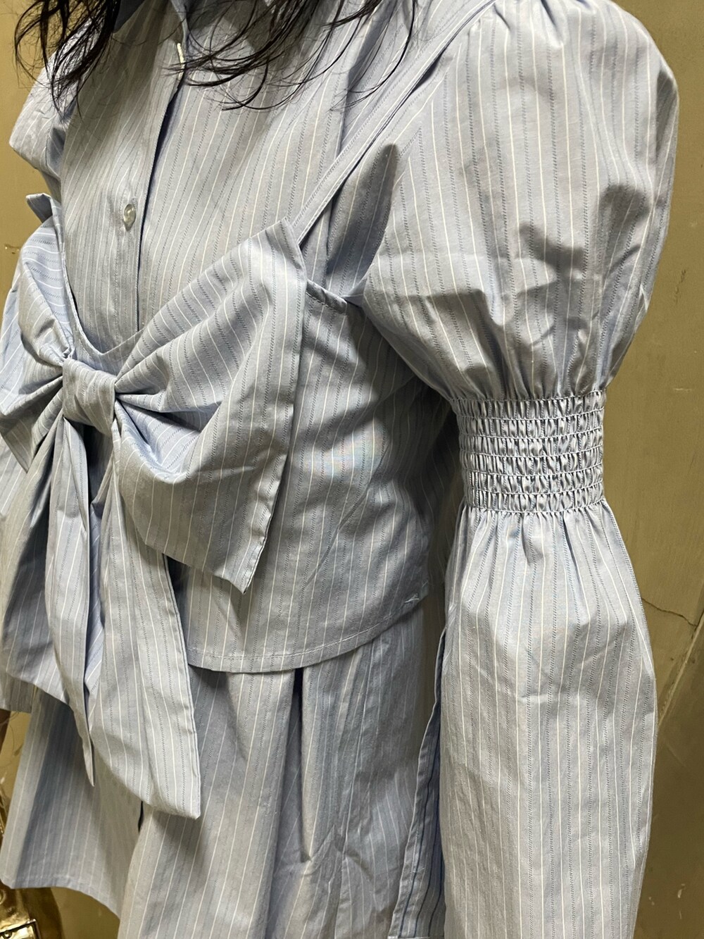 ブルー系のシャツワンピース、ゴールド系のハンドバッグ、ブラック系のブーツを着用したレディースの夏コーディネートの7枚目の写真