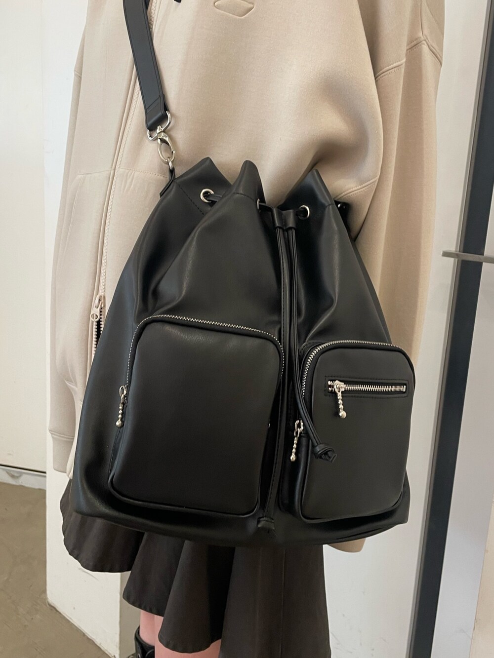 ホワイト系のパーカー、ブラック系のバックパック/リュック、ブラック系のスカートを着用したレディースの冬コーディネートの7枚目の写真